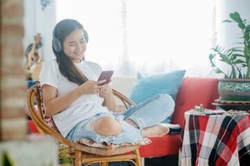 Young woman listening to music while sitting on sofa in room.