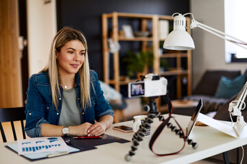 Young business woman recording video for her vlog at home.