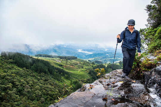 Woman exploring small waterfall in the mist of Sri Lankan highlands