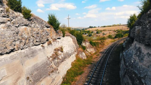 Railway between stones walls with a bridge in the fields of Moldova. Aerial drone view. Sunny day