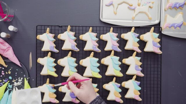 Time lapse. Flat lay. Step by step. Painting food glitter on top of unicorn sugar cookies with royal icing.