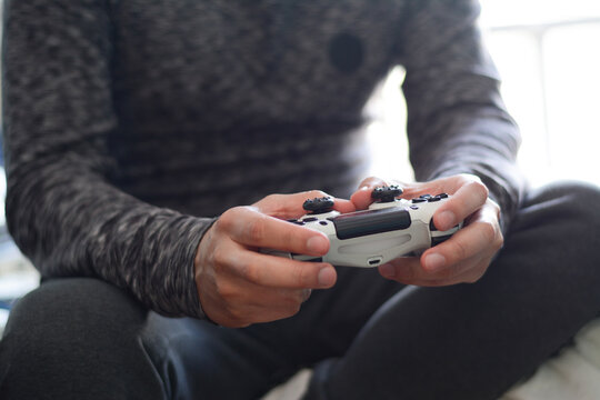 A man holding a game controller. A young man playing video games,