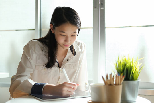 Young student girl using degital pen write on tablet.