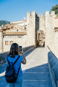 girl taking a picture on the medieval bridge of Besal√∫
