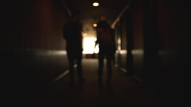 Back view of Caucasian young couple walking hotel hallway. blurred background