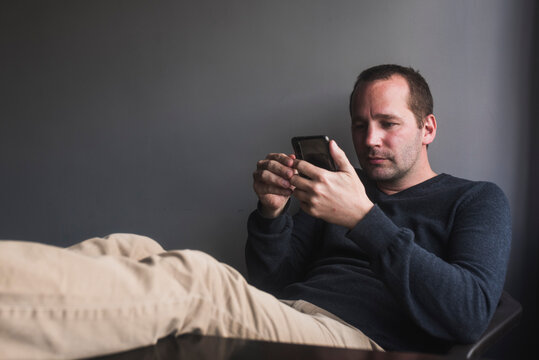 Relaxed man checking his smartphone at home