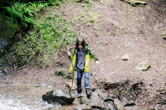 High level view boy climbing over rocks by river at waterfall