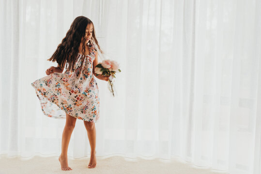 Gorgeous multi racial girl dancing in a dress in front of a curtain