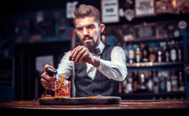 Focused barman creates a cocktail at bar