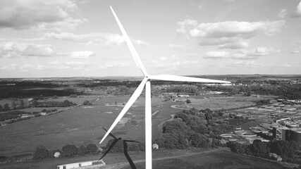 Wind turbine, industrial area agricultural fields in background, clean energy production, black and white aerial view. - 392078649