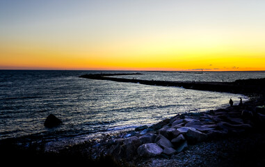 Ocean jetty in Narragansett, Rhode Island under dramatic sky.