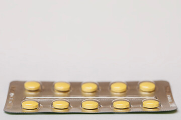Yellow pills in a blister on a light background. Traditional medicine.