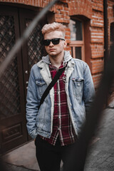 Fototapeta na wymiar guy in the city with glasses near the wall