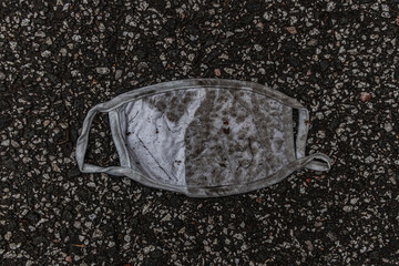 Dirty white Corona face mask carelessly thrown away