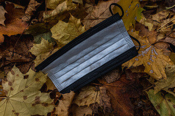 Black and white Corona face mask carelessly thrown away