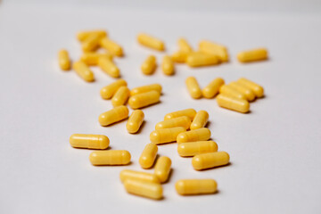 Yellow capsules with medicine are scattered on a white background.