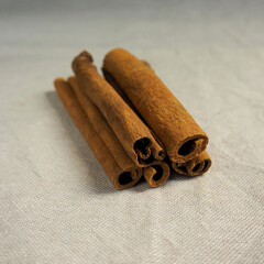 five brown cinnamon sticks lie against a gray linen cloth side view