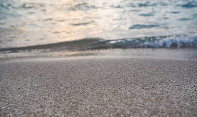 Beach sand near washed by sea water lit by morning sun, low angle closeup detail - abstract marine background