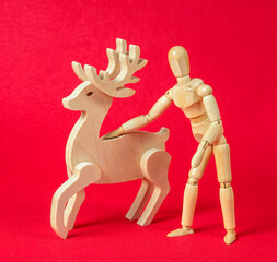 Christmas concept - wooden mannequin with a deer on a red background