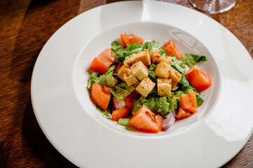 Caesar salad with croutons, quail eggs, cherry tomatoes and grilled chicken in wooden table