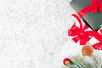 Gift boxes or presents with a bow from the red ribbon, envelope with a letter with a wax stamp for Santa Claus, fir branch on the snow with copy space. Christmas or New Year greeting card concept