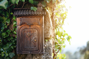 Rustic wooden mailbox at the entrance of the house with vine