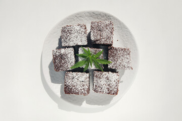 Chocolate marijuana cakes with hemp leaf on white background. Medical marijuana. Concept of herbal alternative medicine. Delicious space candys. Copy space.