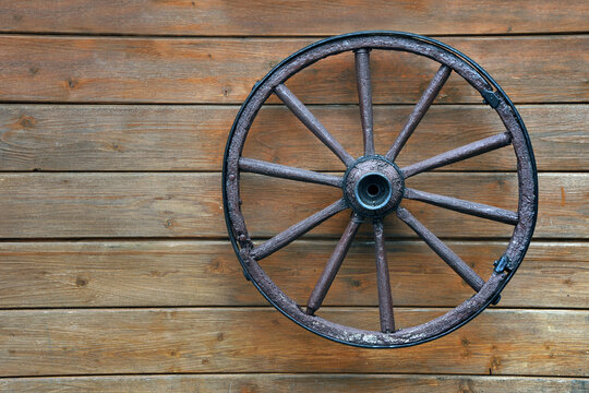 Old wooden wagon wheel hanging on a wall © Mykola