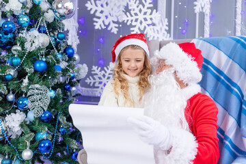 Santa Claus reads a letter from a child at the Christmas tree, new year and Christmas concept