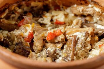 Homemade baked meat, wild mushrooms with vegetables and sour cream closeup in a ceramic pot. Scandinavian traditional dish