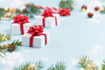 Fir tree branches, red cranberries, christmas gift boxes and candy canes on pastel paper blue background.