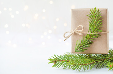 branch spruce and gift in craft paper on light background with bokeh