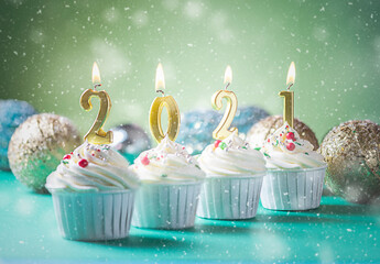 Golden candles in the shape of numbers 2021 on cupcakes. Happy New Year, Merry Christmas and winter...