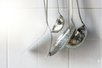 Metal kitchen utensils hanging on the tiled kitchen wall