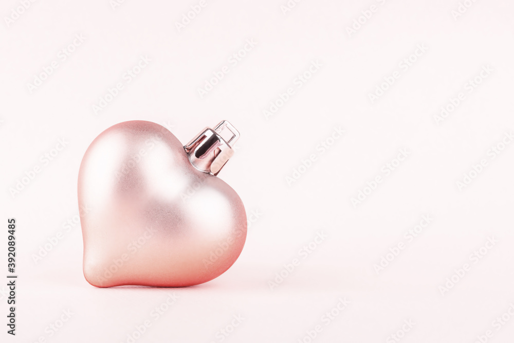Wall mural christmas tree toy in the shape of a heart on a pale pink background with copy space. close up.
