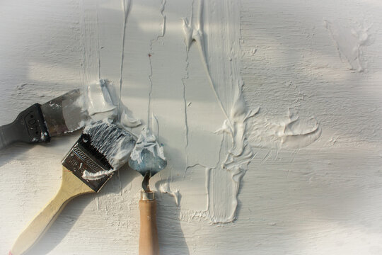 White painted wall. Brushes and painting tools lie on the painted surface. brush and paint