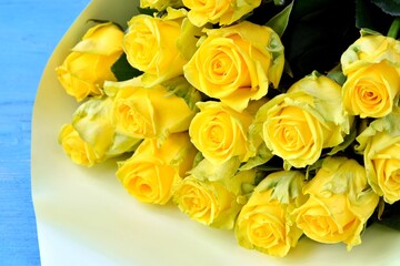 Beautiful Bouquet of fresh yellow roses on blue wooden background with empty space, selective focus. Bunch of yellow flowers. Birthday or holiday bouquet