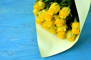 Beautiful Bouquet of fresh yellow roses on blue wooden background with empty space, selective focus. Bunch of yellow flowers. Birthday or holiday bouquet