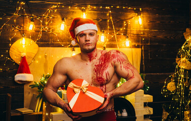 Hot man holding a heart shaped gift box. Devil hot sales concept. A bloody Christmas scene from...