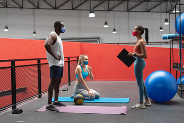 caucasian female fitness trainer holding stopwatch and clipboard instructing fit african american m