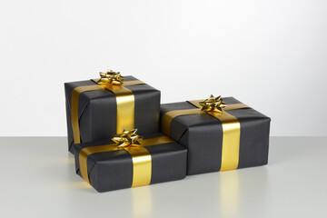 Cajas de regalo de color negro con lazo dorado sobre fondo blanco