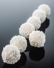 white chocolate truffles on black surface with reflection, selective focus