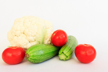 Various raw vegetables with water splash. Cauliflower, tomato, cucumber, radish and paprika on a green background.