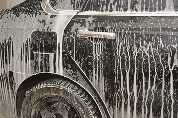 The car body is covered with soap suds to remove dirt. Car wash