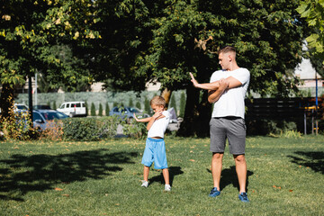 Obraz premium Father and son in sportswear warming up before training in park