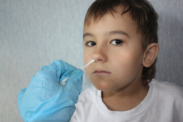 The child is tested for coronavirus. Hand in a glove with a cotton swab. portrait of a boy