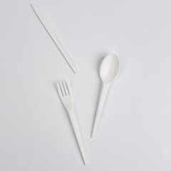 disposable plastic utensil fork spoon knife on white background. Look from above