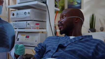 Unhealthy african american patient with nasal cannula listening to doctor explantions coronavirus symptoms infection disease talking at hospital room. Medical concept.