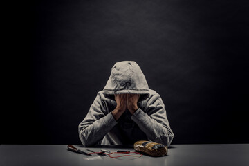 The addict hides his face from the camera. Concept of crime and drug addiction.