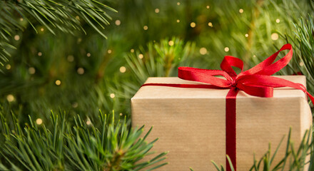 Fototapeta na wymiar Gift box on Christmas tree with defocused lights